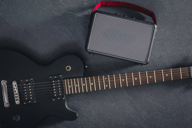 istock Electric guitar and speaker on a textured black background, top view. 2096607948