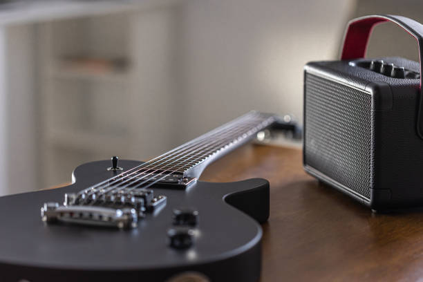 istock Black electric guitar and speaker on a wooden table. 2096607949