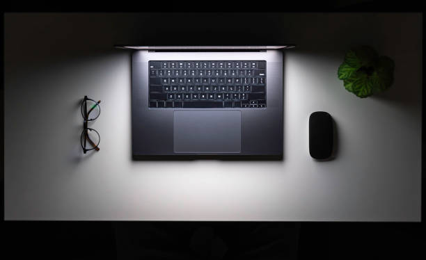 istock Laptop, computer mouse and glasses on a white table at night, top view. 2096610570