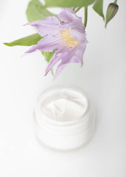 open jar of cream with  flower hanging over it.