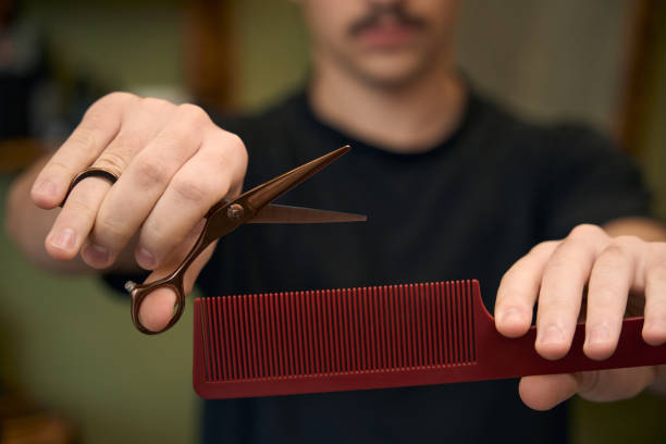Blurred barber showing scissors and hairbrush in barbershop