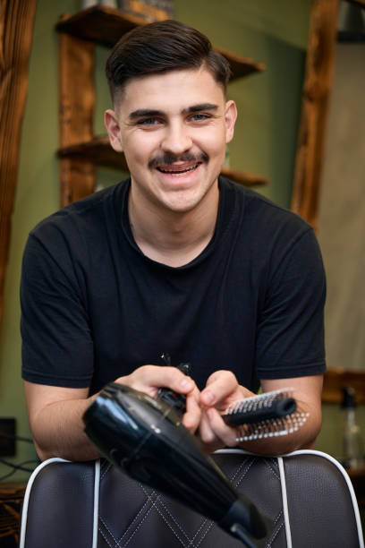 istock Smiling man coiffeur holding comb and hair dryer 2096631448