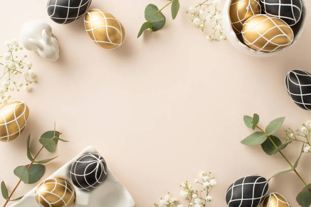 istock Deluxe Easter scenario: top-down view of plush black and gold eggs in a clay holder, ceramic rabbit, eucalyptus shoots, gypsophila, laid on a pastel beige palette, gap for text 2096635789