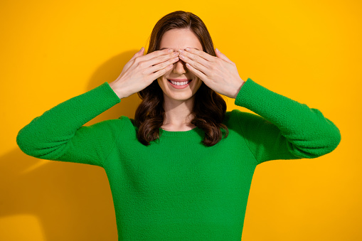 Photo of cheerful carefree girl wear stylish green clothes two arms cover eyes isolated on yellow color background.