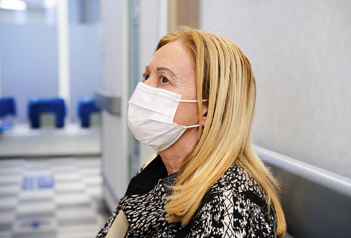 A female patient with a face mask waiting in the empty hospital. Health insurance