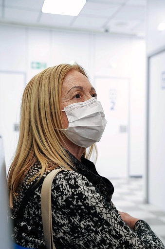A female patient wearing a mask is waiting the medical treatment in a waiting room of hospital