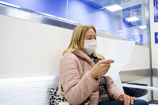 A female patient wearing a mask reading a medical diagnostic in a health clinic. Health insurance