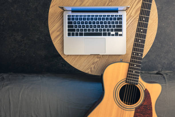 istock Acoustic guitar and laptop on a wooden table, top view. 2096661143