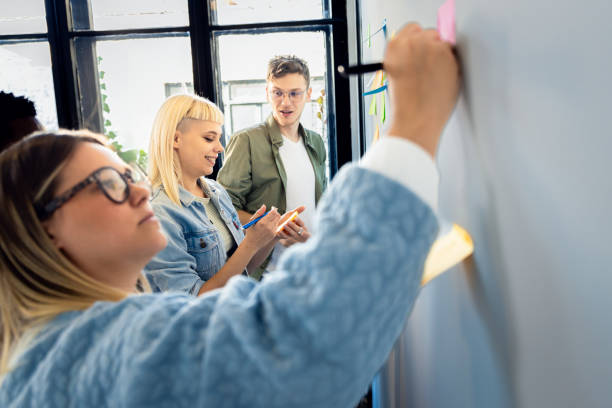istock Diverse group of young business people working in office using colorful sticky notes on wall to organize their ideas. 2096668116