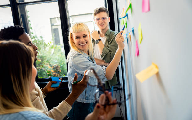 istock Diverse group of young business people working in office using colorful sticky notes on wall to organize their ideas. 2096676091