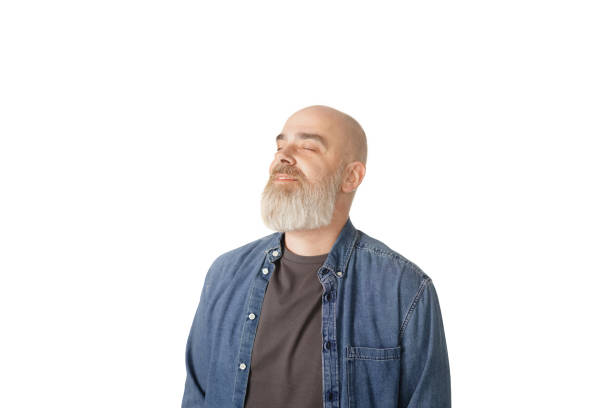 Close-up view of a senior man with a thoughtful expression, looking up, highlighting his white goatee against a bright background