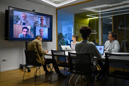Business people having video conference meeting in board room.