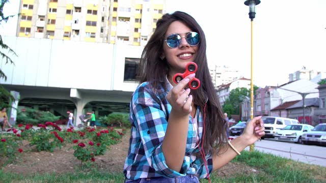 Young Hipster Woman Playing With Fidget Spinner Outdoors