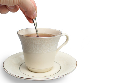 Stirring a cup of tea with a spoon on a white background