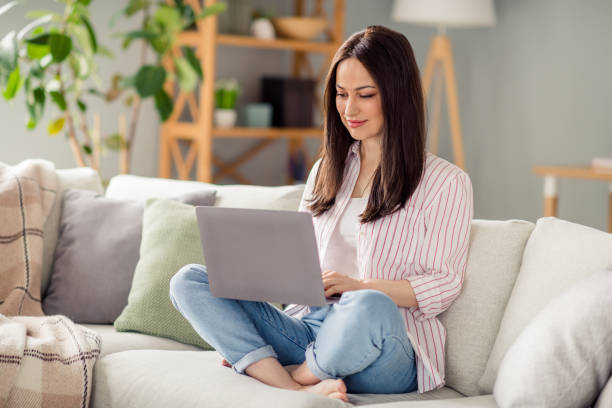 istock Full body photo of nice barefoot lady sit couch use netbook coworking write email modern flat inside 2096690053