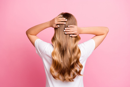 Rear back behind view portrait of lovely woman dressed stylish t-shirt hands touching wavy hairdo isolated on pink color background.