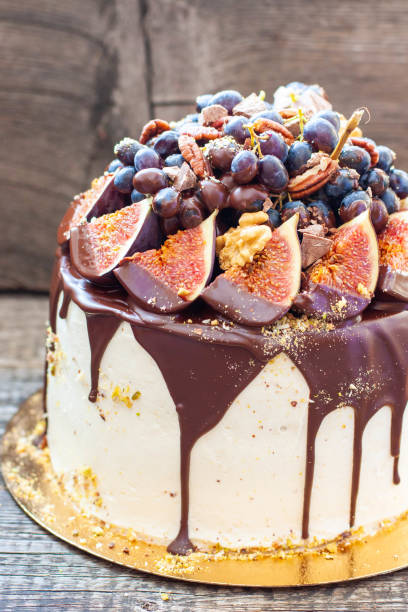 istock Beautiful cake with figs dipped into melted chocolate, pecan nuts, grapes, chocolate bites and cookies on the top on rustic background 2096722841