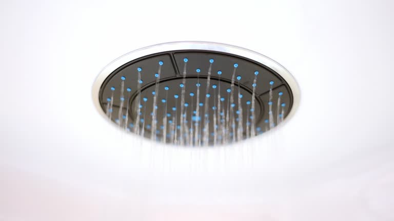 Water flows slowly from a round, stylish shower head. The concept of luxury plumbing in the bathroom, comfort, modern design.