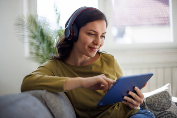 istock Smiling relaxed woman resting on couch and using digital tablet 2096737604