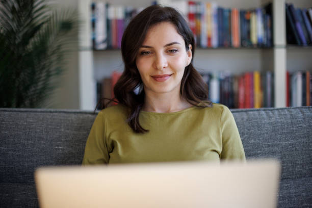 istock Smiling young woman using laptop at home 2096737609