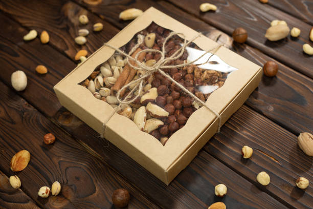 Nuts of different varieties in a box on a structural wooden background top view.