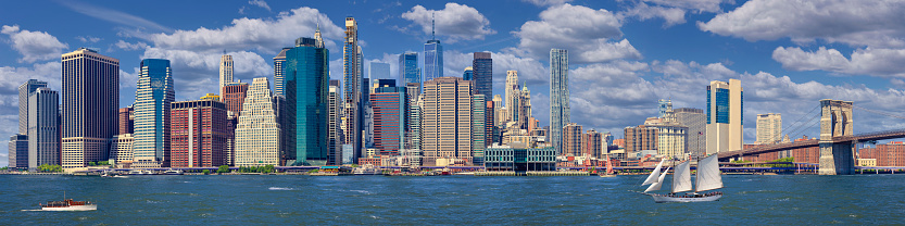 Stitched Panorama of Manhattan Lower East Side Financial District, Brooklyn Bridge, World Trade Center, Blue Sky with Clouds and Water of East River, New York, USA. Canon EOS 6D (Full Frame censor) DSLR and Canon EF 85mm f/1.8 Prime Lens. 4:1 Image Aspect Ratio. This image is downsized to 50MP. The Original image resolution is 111MP or 21,088 x 5,272px.