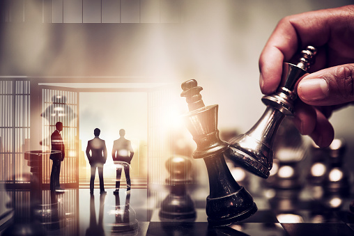 double exposure of chess piece on chess board game with silhouette business team and strategy, business success concept, business competition planning teamwork strategic concept.