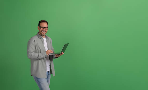 istock Successful happy male manager working over laptop while standing confidently on green background 2096796016