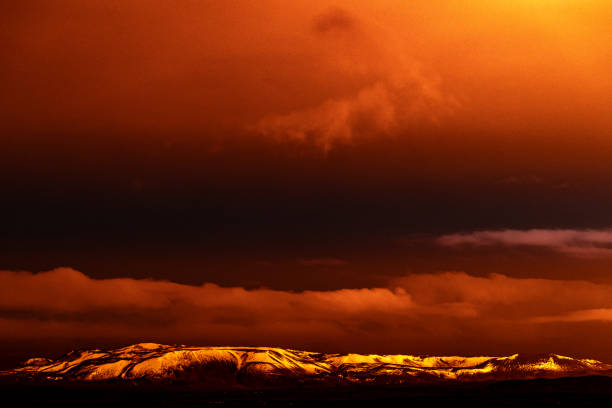 Mountains glowing in red from the volcano eruption at night time near Grindavik in Iceland