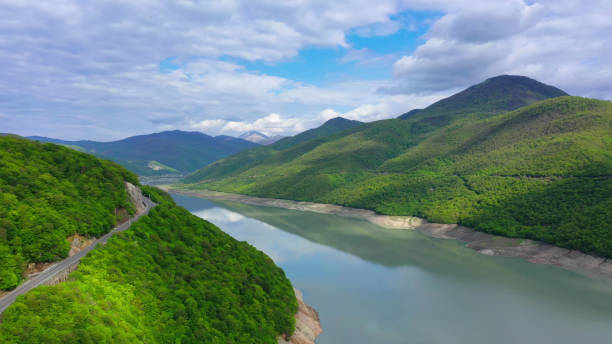 Mountain road. Pond among the mountains covered with forest. Aerial view