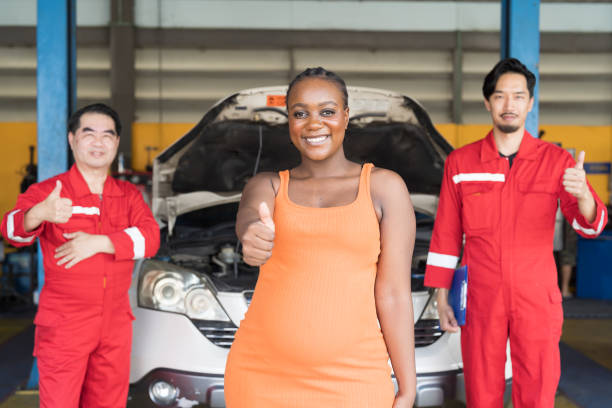 glückliche und lächelnde männliche mechaniker und weibliche kundin bei autoreparaturservice. autoservice- und wartungskonzept - car old african descent car salesperson stock-fotos und bilder