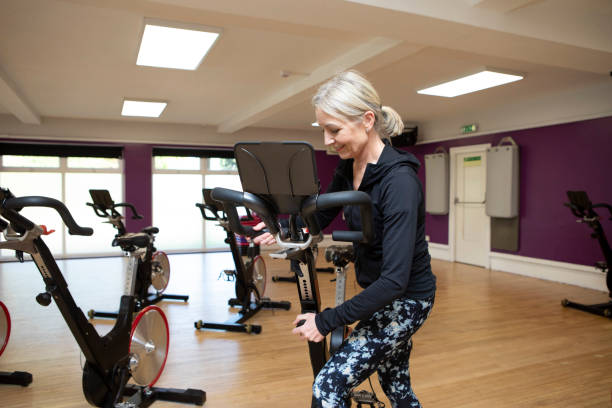 istock Woman setting up an exercise bike in a gym 2096856603