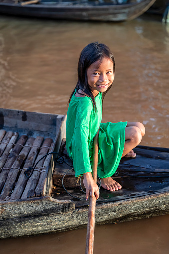 Cambodian girl rowing a boat in village near Tonle Sap, Cambodia