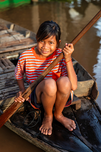 Cambodian girl rowing a boat in village near Tonle Sap, Cambodia