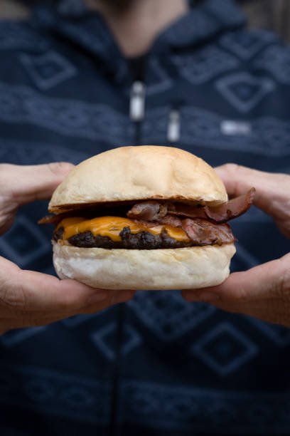 istock A man holding a delicious cheeseburger with bacon 2096872867