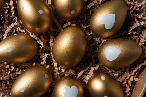 Close-up view of Golden eggs in paper box on a dark table.