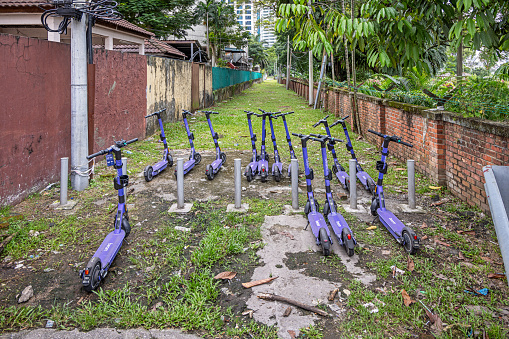 Kuala Lumpur, Malaysia - January 8th 2024:   Group of electrical rental push scooters in side street in the center of the Malaysian capital