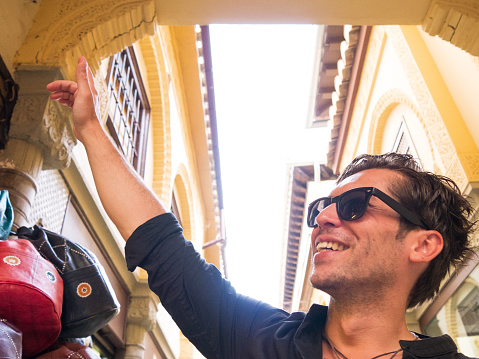 Smiling handsome man with sunglasses and black shirt at handicraft market in Granada Spain pointing up left