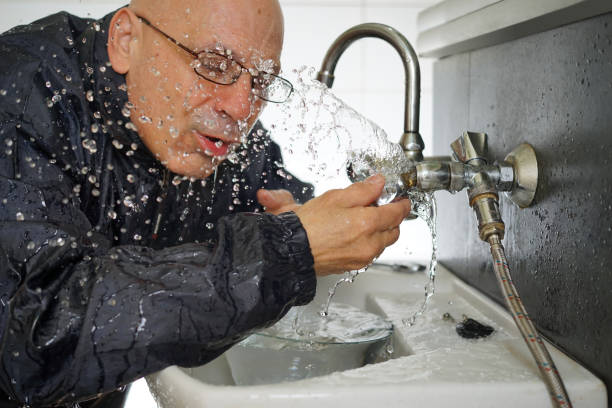 A man has a problem with a damaged faucet in a bathroom.