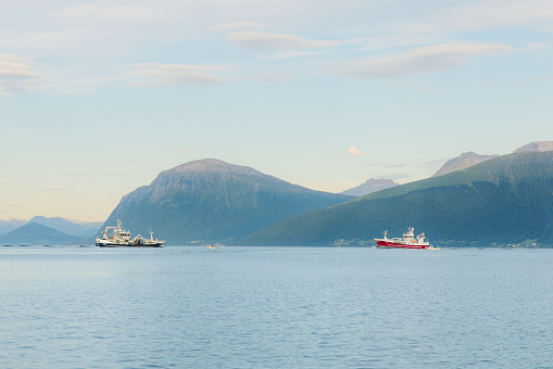 Scenic view of two fishing boats sailing to each other in the sea with view of the summer mountains in Sunnmore Alps, Scandinavia