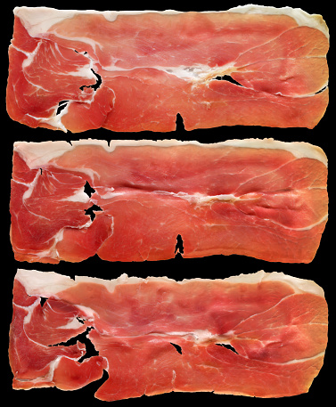 Three slices of gourmet delicious Prosciutto ham isolated on black background, high resolution stock image.