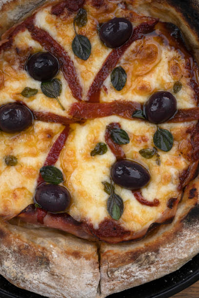 Cutting and decorating rustic homemade pizza on wooden base