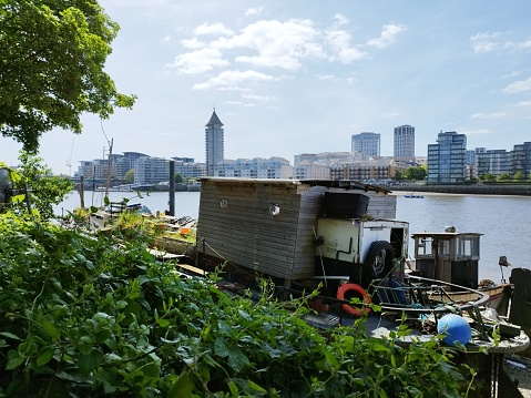 Houseboat and new-build apartments along the river depicting multiple ways of life