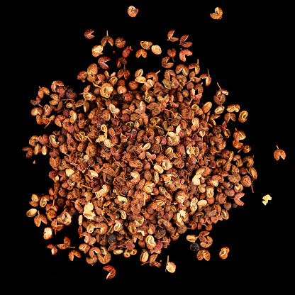 Pile of Sichuan Chinese pepper isolated on black background, shot from above