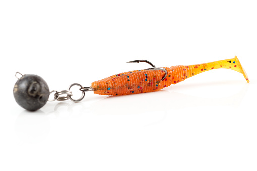 Orange fishing lure, plastic shad fish, with double hook and lead sinker, isolated on white background