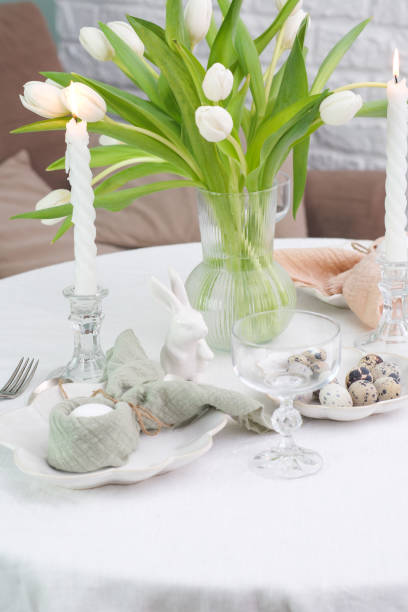 istock Beautiful table serving for Easter celebration in dining room, candles, glasses, plates with easter eggs and bunny, vase with flowers. Easter table setting. 2097022569