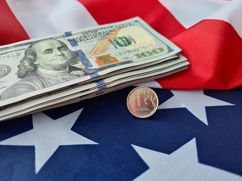 A stack of money is placed on top of an American flag, symbolizing financial wealth and patriotism. The crisp bills contrast with the flags red, white, and blue colors.