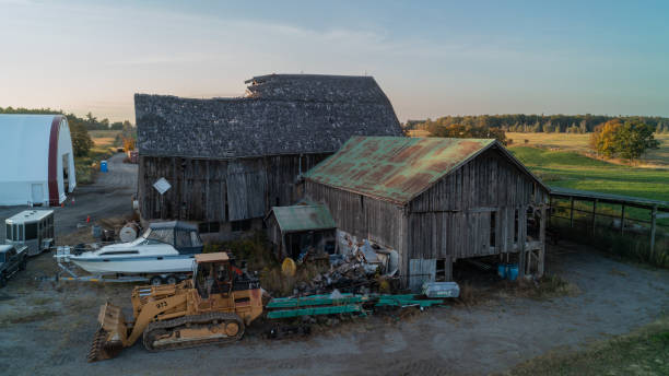 An aerial shot of a dilapidated Barn on a farm at sunset