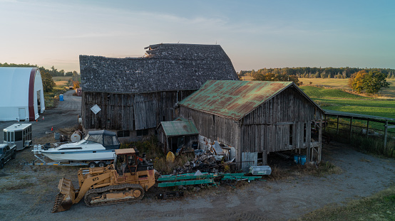 An aerial shot of a dilapidated Barn on a farm at sunset