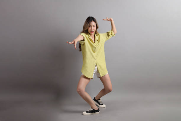 The Asian woman in casual dressed standing on the grey background.